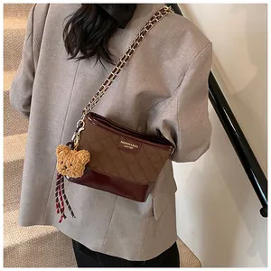 Détail du sac à bandoulière vintage avec matelassage marron et breloque ours en peluche