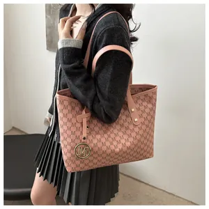 Detail of pink tote bag with M-pattern print and golden metal charm on strap