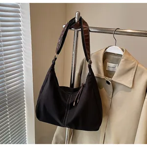 Detail of dark brown canvas tote bag with contrast stitching and leather strap hanging