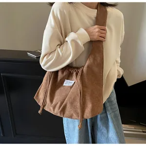 Détail d'un sac cabas en velours côtelé marron avec fermeture à cordon et sangle