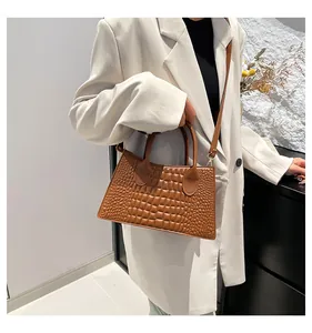 Borsa a mano marrone con stampa coccodrillo abbinata a un blazer bianco per un look moderno