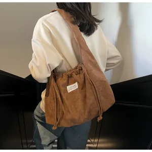 Détail d'un sac cabas en velours côtelé marron avec cordons de serrage et larges bandoulières
