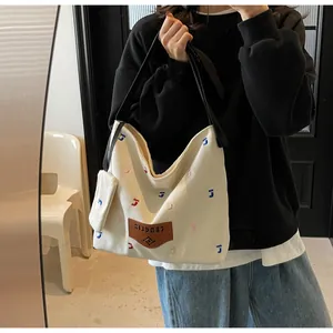 Detail der Canvas-Hobo-Tasche mit bunter Stickerei, Lederanhänger und Gurt