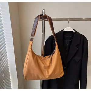 Detail view of large brown canvas tote bag featuring textured fabric and wide leather strap