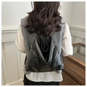 Détail d'un sac à dos pliant noir minimaliste en cuir brillant porté par un mannequin