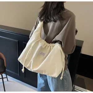 Gros plan du sac cabas en velours côtelé écru avec fermeture à cordon et étiquette
