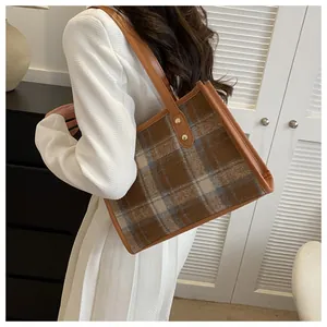 Classic checkered tote bag detail with brown leather straps and gold rivets for autumn