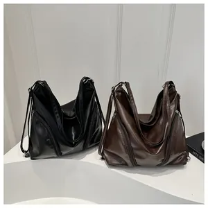Gros plan de sacs cabas en cuir noir et marron foncé sur un socle blanc pur