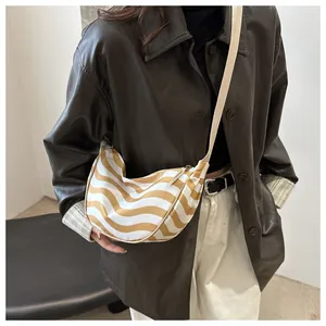 Detail of a chic half-moon crossbody bag with wavy stripes on a stylish female model