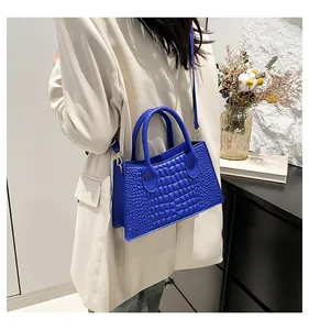 Dettaglio della borsa blu con motivo goffrato, hardware dorato e doppie tracolle
