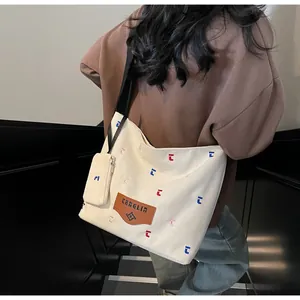 Detailansicht der cremefarbenen Canvas-Tote Bag mit bunter Stickerei und Mini-Anhängertasche