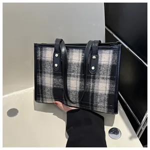 Close-up of black and white plaid wool tote bag with black leather handle and silver buckle