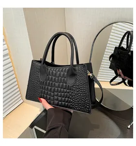 Dettaglio di una borsa a tracolla trapuntata nera tenuta in mano vicino a uno specchio