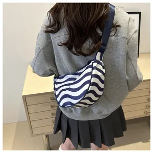 Detail of blue and white striped half-moon crossbody bag shown on a model