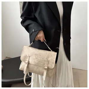 Detail of beige vintage satchel with metal buckles and flap texture on model