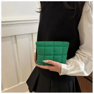 Detail of green quilted puffer handbag featuring minimalist square stitching and soft nylon fabric