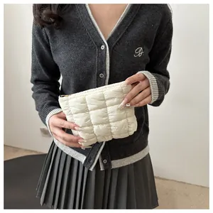 Detail of white quilted mini cosmetic bag with gold zipper and puffy square stitching