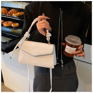 Detail of white handbag with embossed lotus texture and knotted handle in a lifestyle setting