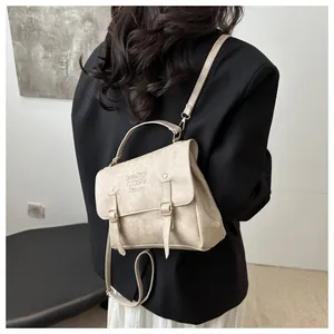 Rear view of model wearing a creamy white faux leather backpack with metallic buckle detail