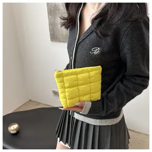 Detail of a bright yellow quilted puff cosmetic bag with zip closure and grid texture