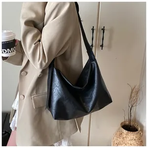 Detalle del bolso tote vintage negro grande con textura plisada en una modelo