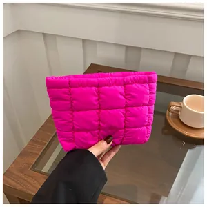 Macro detail of hot pink quilted puffer clutch bag showing soft padded square stitching