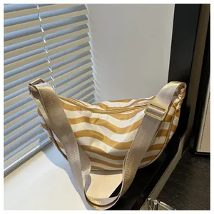 Detail of a yellow striped crescent shoulder bag with adjustable strap on white surface