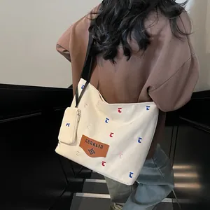 Cremeweiße Canvas-Tragetasche mit Stickereien und Leder-Patch in Modell-Rückansicht