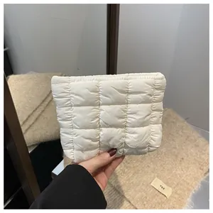 Detail of quilted puffy makeup bag in cream white showing soft nylon texture and stitching