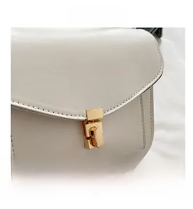 Detailansicht einer weißen Lederhandtasche mit goldener Schnalle und Ziernähten
