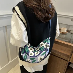 Floral crossbody dumpling bag with adjustable strap shown on model in cozy cafe