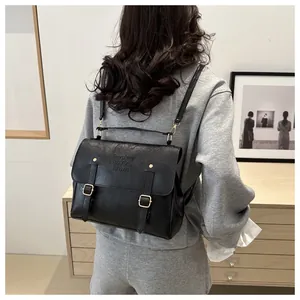 Dettaglio zaino vintage in pelle nera con logo in rilievo e finiture in metallo oro