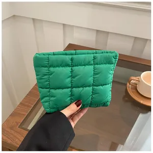 Close-up of green quilted puffy handbag held by hand in a cozy lifestyle setting