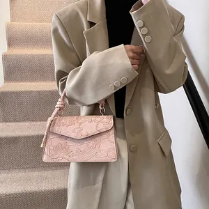 Minimalist pink embossed handbag with floral motifs shown as a shoulder bag on a model