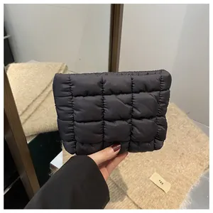 Detail of hand-held black quilted square clutch bag with puffy lattice stitching