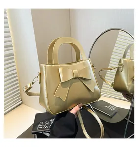 Borsa a mano color champagne con grande fiocco e tracolla che si riflette in uno specchio
