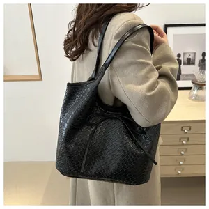 Détail d'un sac cabas noir tressé avec nœud papillon porté sur un élégant manteau beige