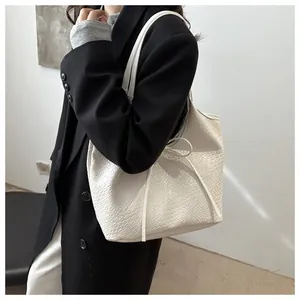 Gros plan sur la texture du grand sac cabas blanc tressé porté par un mannequin