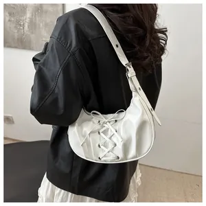 Detalle del bolso de media luna blanco con diseño de cordones y hebillas plateadas