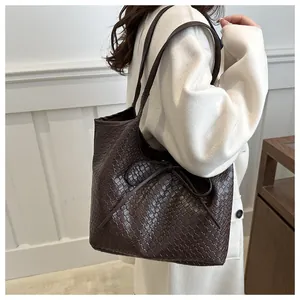 Vue détaillée du sac cabas tressé marron foncé avec un nœud décoratif en cuir souple