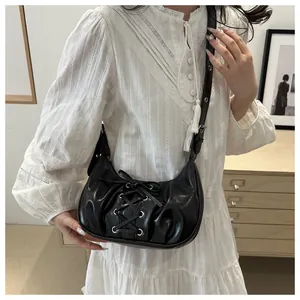 Detalle del bolso de media luna en cuero sintético negro con cordones y pliegues