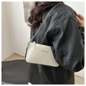 Detail of off-white envelope bag featuring silver bead rivets and a metallic chain strap
