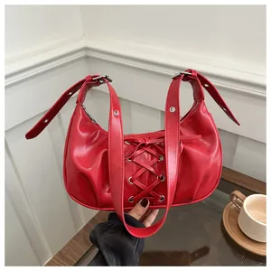 Detalle de bolso medialuna rojo con cordones estilo corsé y ojetes metálicos