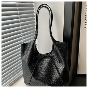 Gros plan détaillé de la texture en cuir tressé noir et du nœud élégant sur le sac cabas