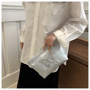 Dettaglio della trousse in raso azzurro con ricamo a farfalla in argento metallizzato