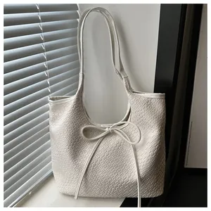 Détail d'un cabas tressé blanc avec un nœud décoratif et une finition texturée élégante