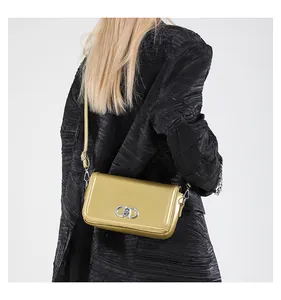 Close-up of metallic gold handbag with silver CD buckle on model wearing black coat