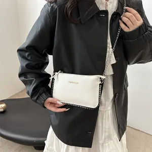 White pebbled leather envelope crossbody bag with gold fashion text and metal rivets
