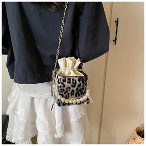 Detail view of leopard print bucket bag featuring a large pearl handle and chain strap