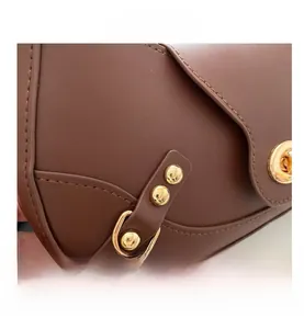 Detail of brown leather bag showing stitching, gold D-ring and metal rotary lock